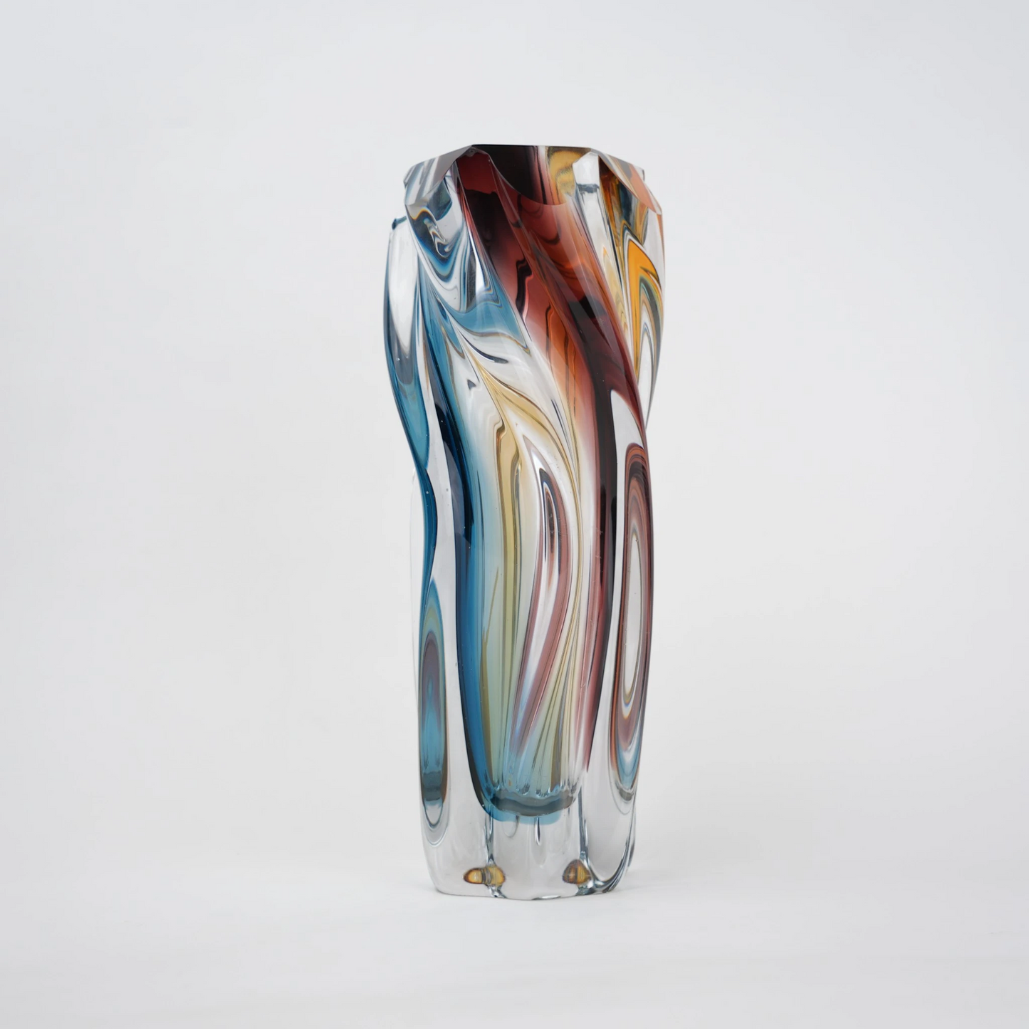 Multicolored twisted sculptural glass vase with elongated form and fluid wave-like contours.