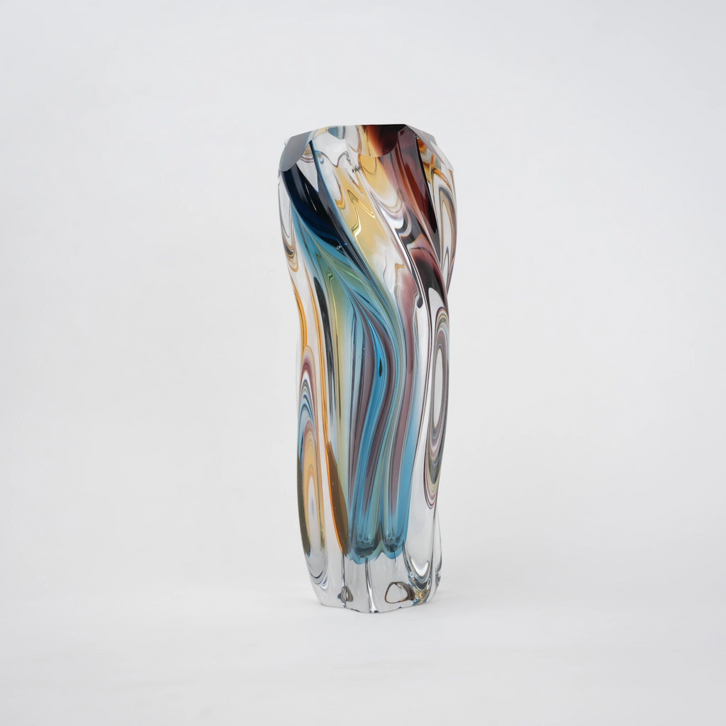 Multicolored twisted sculptural glass vase with elongated form and fluid wave-like contours.