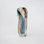 Multicolored twisted sculptural glass vase with elongated form and fluid wave-like contours.