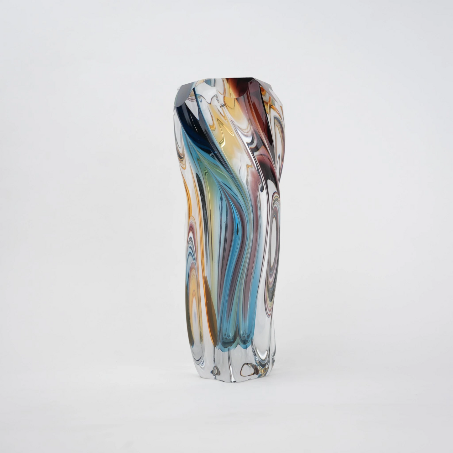 Multicolored twisted sculptural glass vase with elongated form and fluid wave-like contours.