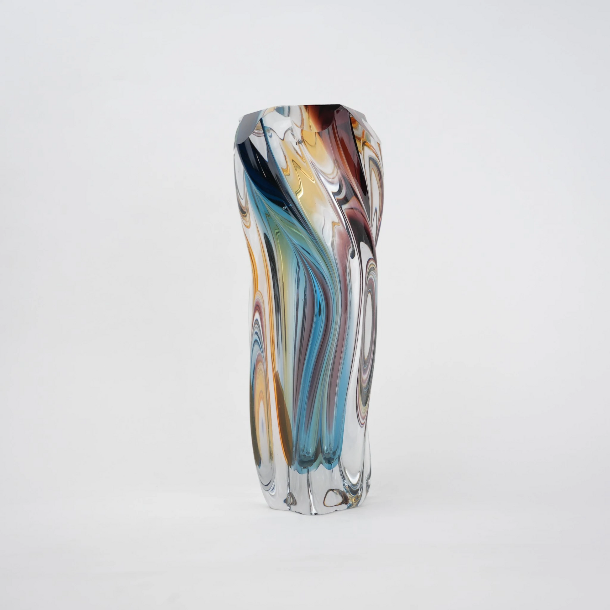 Multicolored twisted sculptural glass vase with elongated form and fluid wave-like contours.