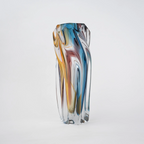 Multicolored twisted sculptural glass vase with elongated form and fluid wave-like contours.