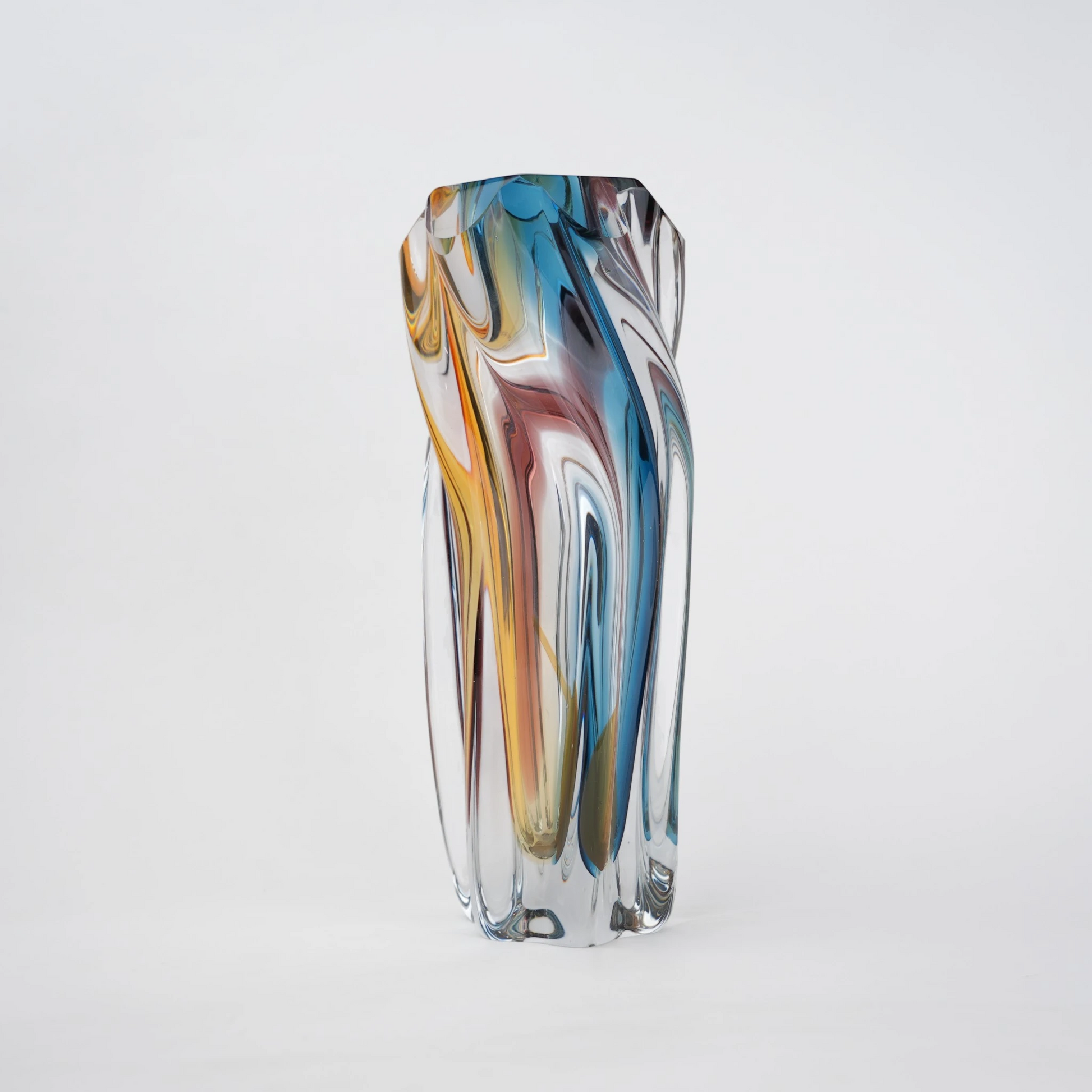 Multicolored twisted sculptural glass vase with elongated form and fluid wave-like contours.