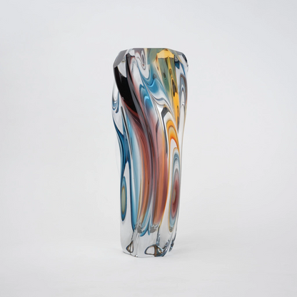Multicolored twisted sculptural glass vase with elongated form and fluid wave-like contours.