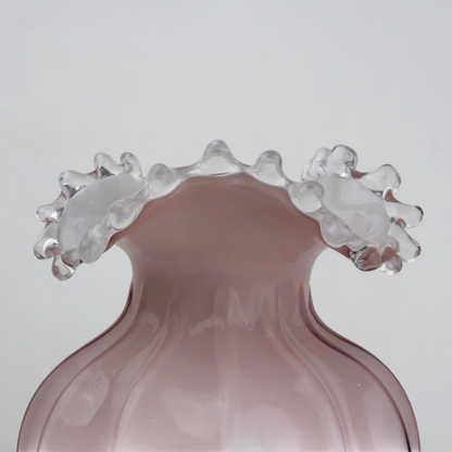 Blush pink translucent glass vase with curved body and sculptural ruffled rim.