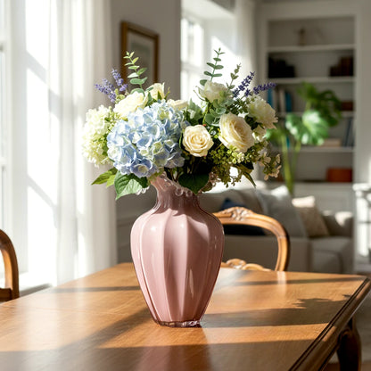 Blush pink translucent glass vase with curved body and sculptural ruffled rim.