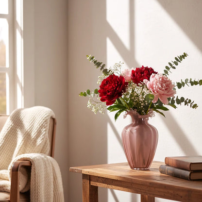 Blush pink translucent glass vase with curved body and sculptural ruffled rim.