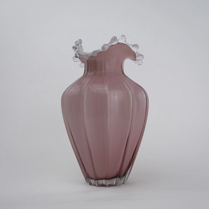 Blush pink translucent glass vase with curved body and sculptural ruffled rim.