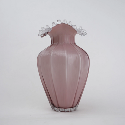 Blush pink translucent glass vase with curved body and sculptural ruffled rim.