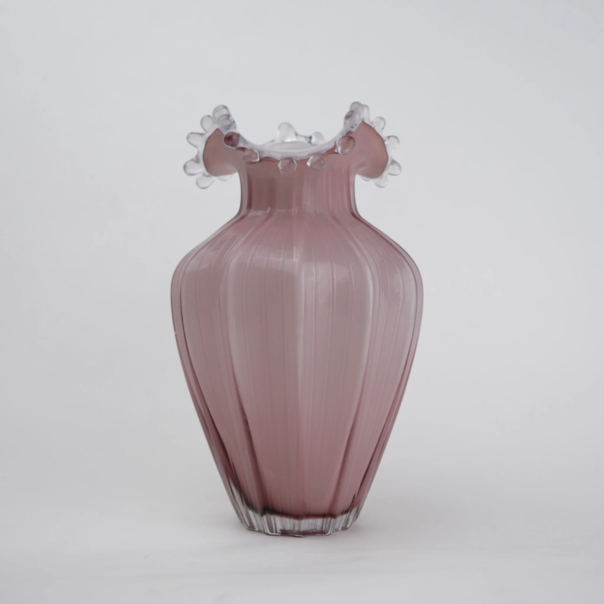 Blush pink translucent glass vase with curved body and sculptural ruffled rim.