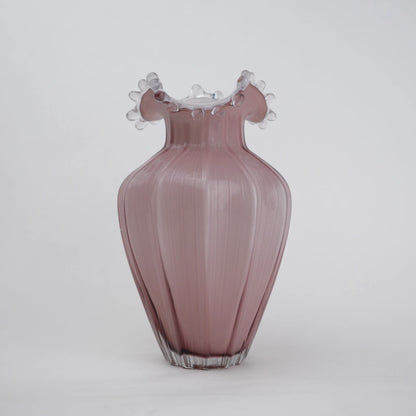 Blush pink translucent glass vase with curved body and sculptural ruffled rim.