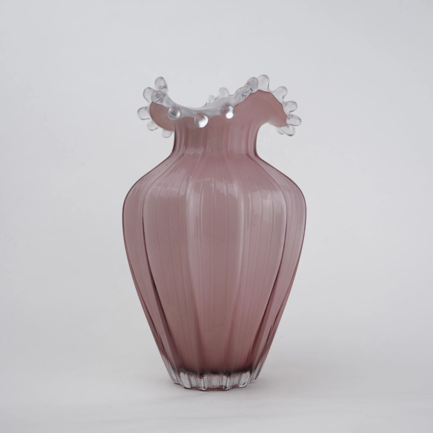 Blush pink translucent glass vase with curved body and sculptural ruffled rim.