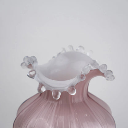 Blush pink translucent glass vase with curved body and sculptural ruffled rim.