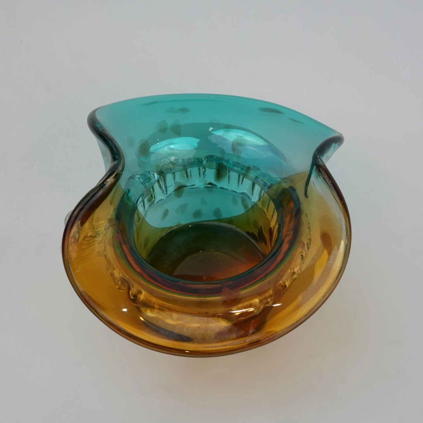 Dual-tone aqua and amber glass vase with sculptural wave-shaped rim and rounded base.