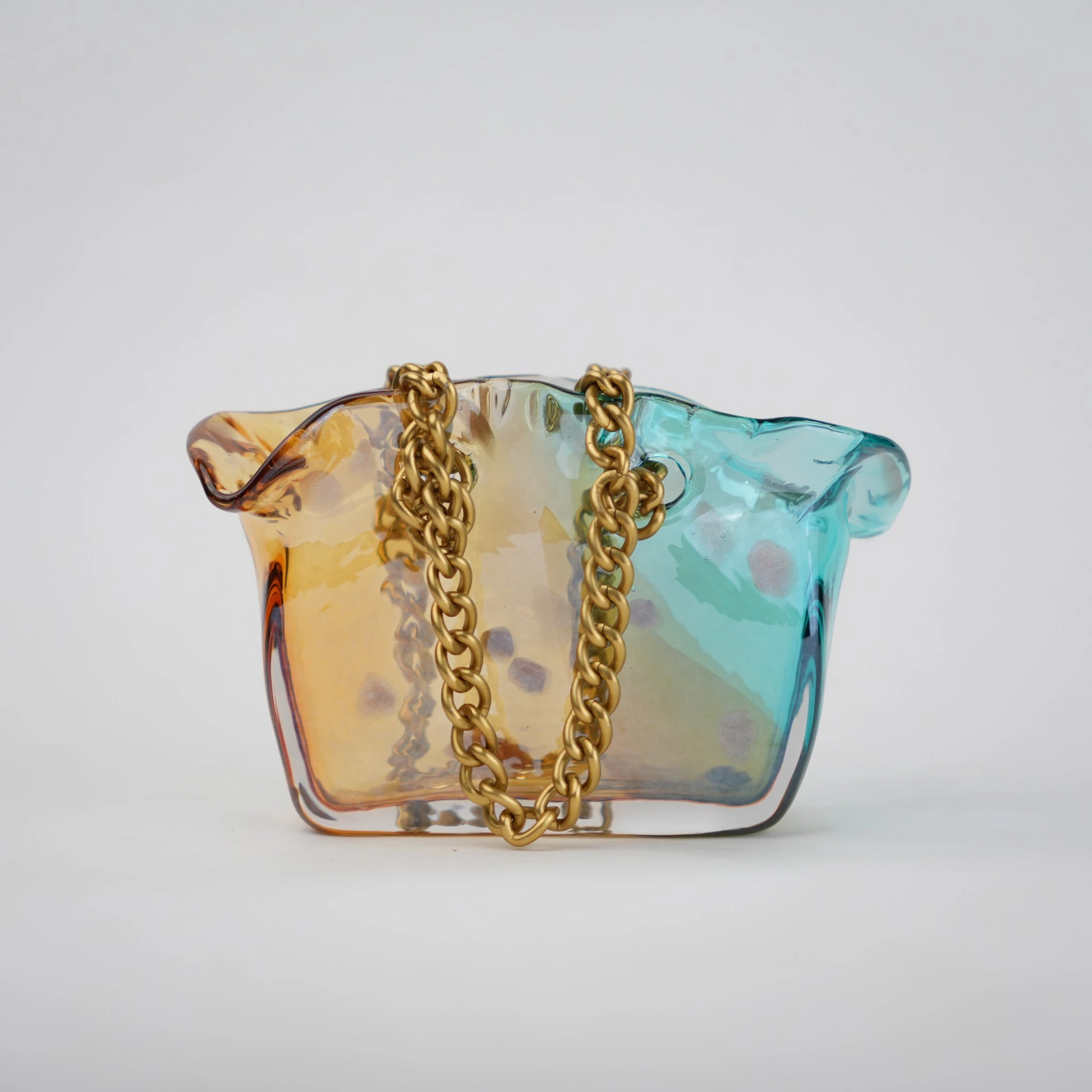 Dual-tone teal and amber glass vase with bubble texture, sculptural form, and metallic chain handle.