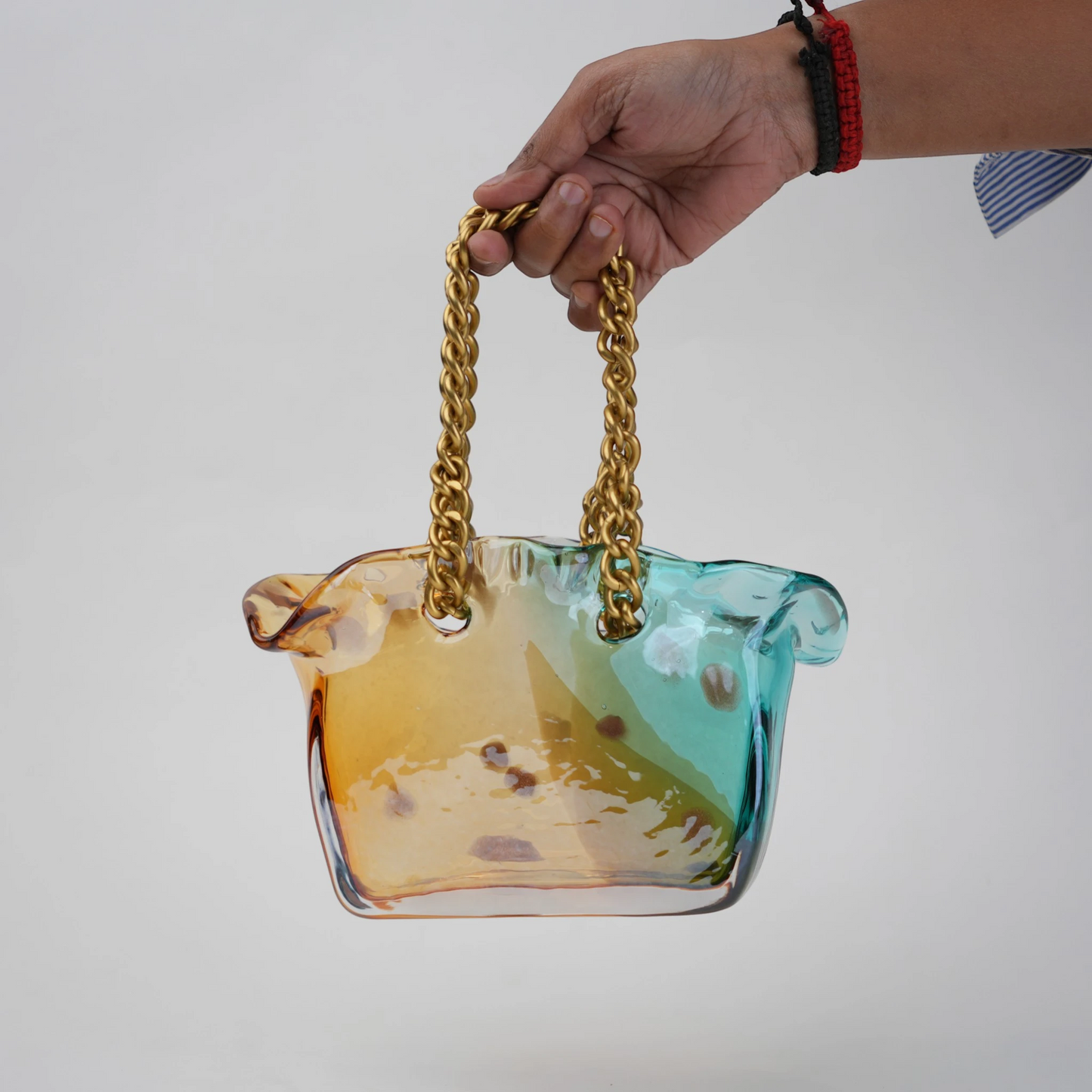 Dual-tone teal and amber glass vase with bubble texture, sculptural form, and metallic chain handle.