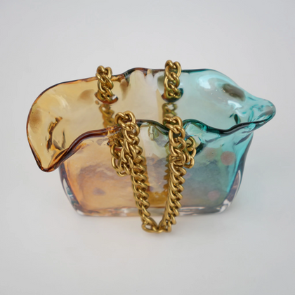 Dual-tone teal and amber glass vase with bubble texture, sculptural form, and metallic chain handle.