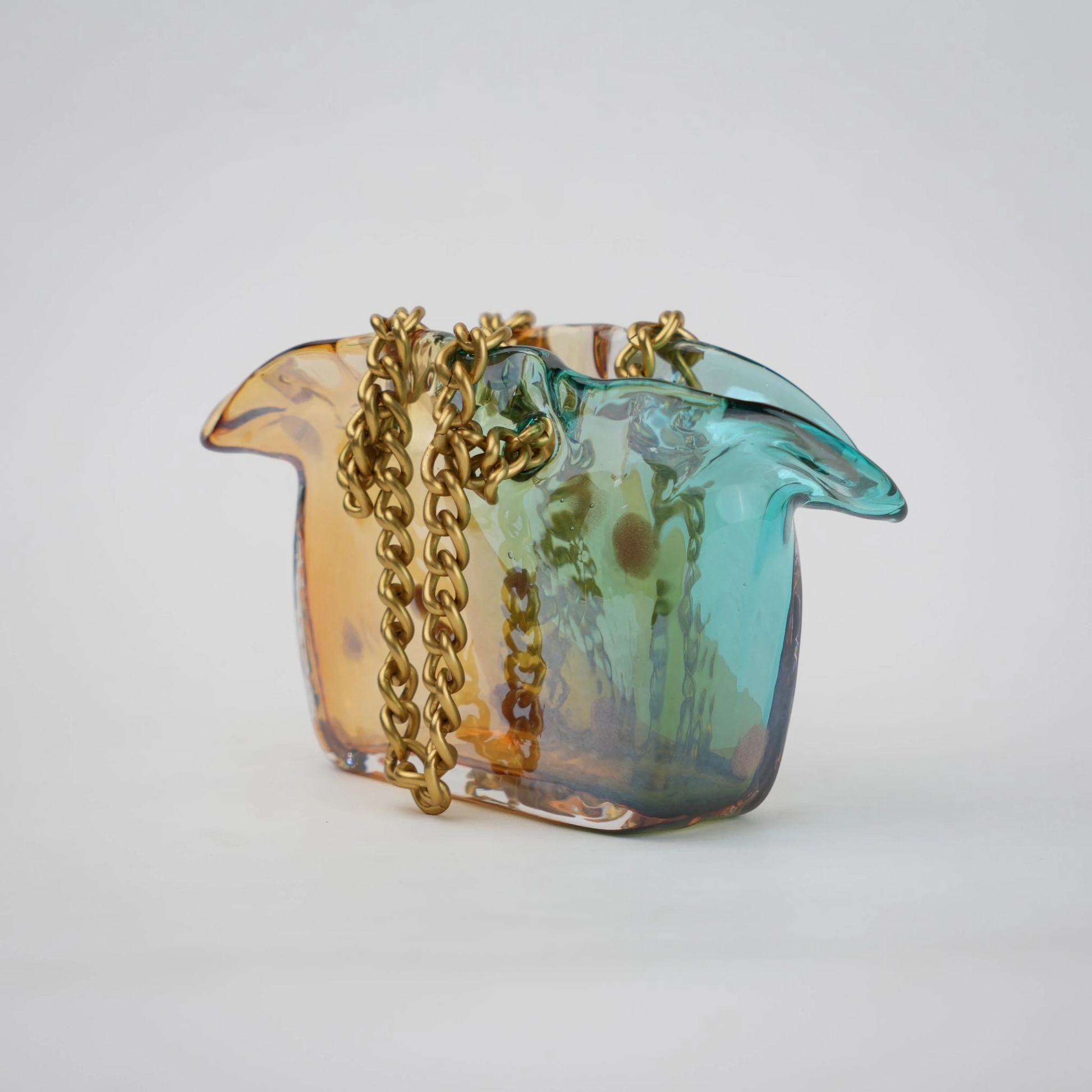 Dual-tone teal and amber glass vase with bubble texture, sculptural form, and metallic chain handle.