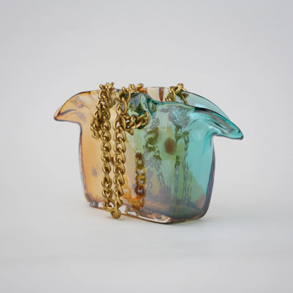 Dual-tone teal and amber glass vase with bubble texture, sculptural form, and metallic chain handle.