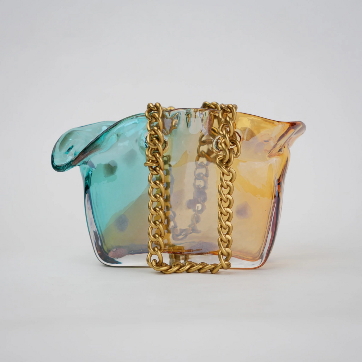Dual-tone teal and amber glass vase with bubble texture, sculptural form, and metallic chain handle.