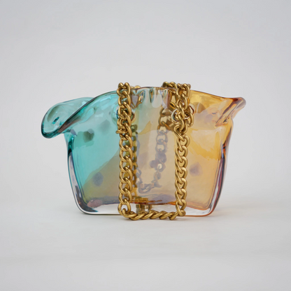 Dual-tone teal and amber glass vase with bubble texture, sculptural form, and metallic chain handle.