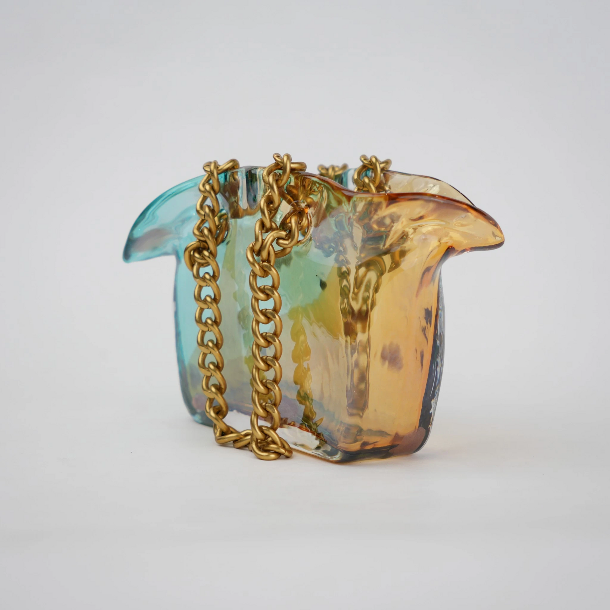 Dual-tone teal and amber glass vase with bubble texture, sculptural form, and metallic chain handle.