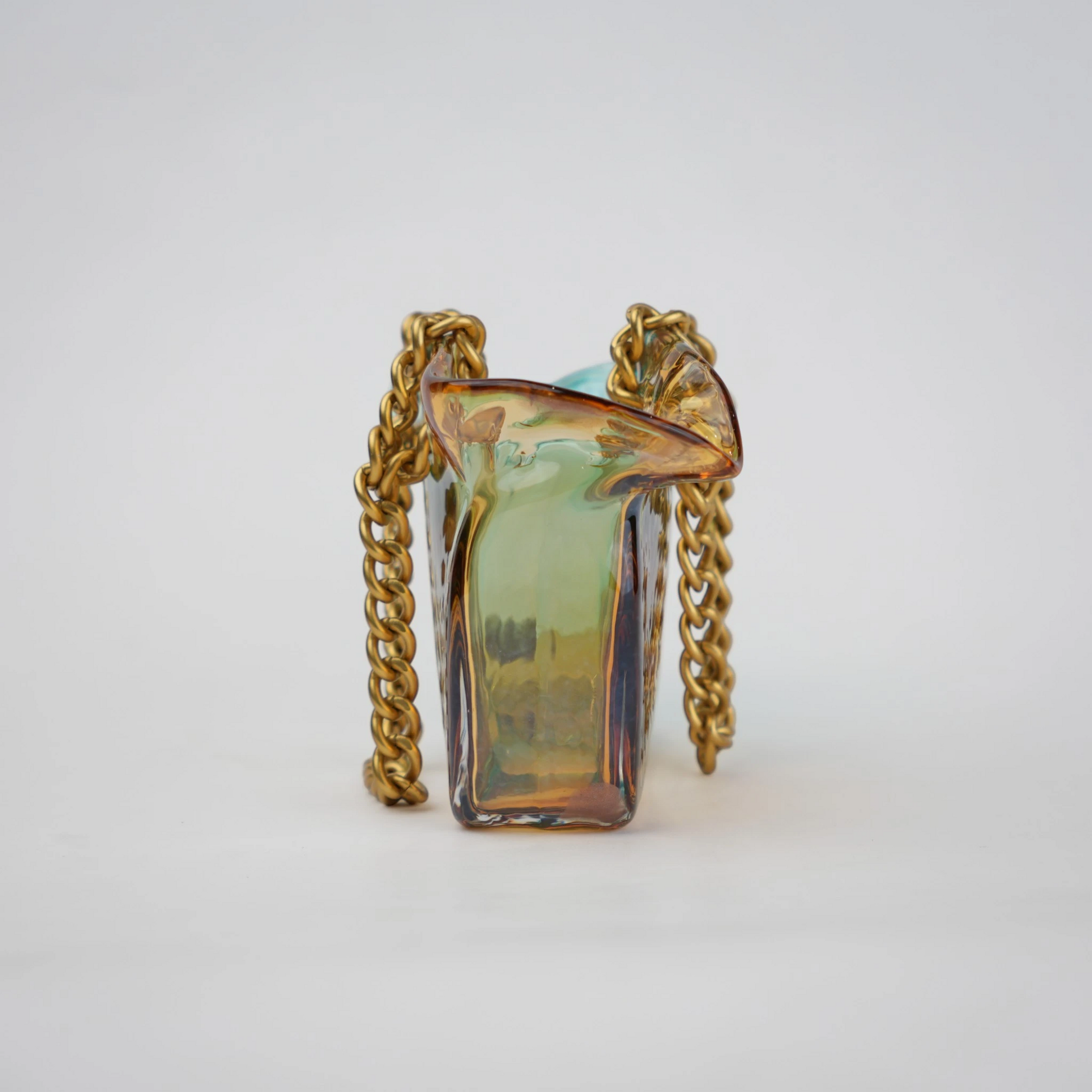 Dual-tone teal and amber glass vase with bubble texture, sculptural form, and metallic chain handle.