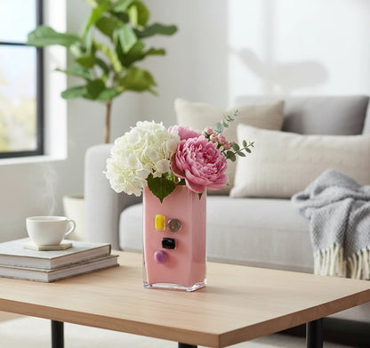 Pink art glass vase with embedded multicolor accents and wide rectangular form.