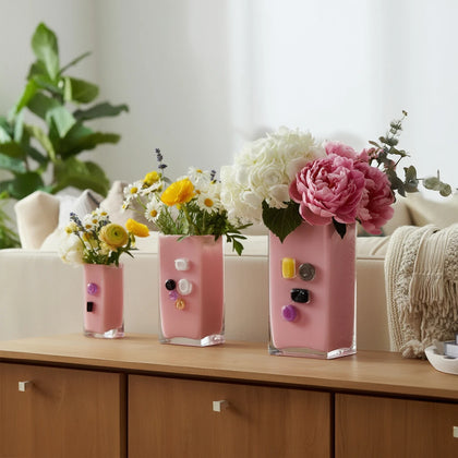 Pink art glass vase with embedded multicolor accents and wide rectangular form.