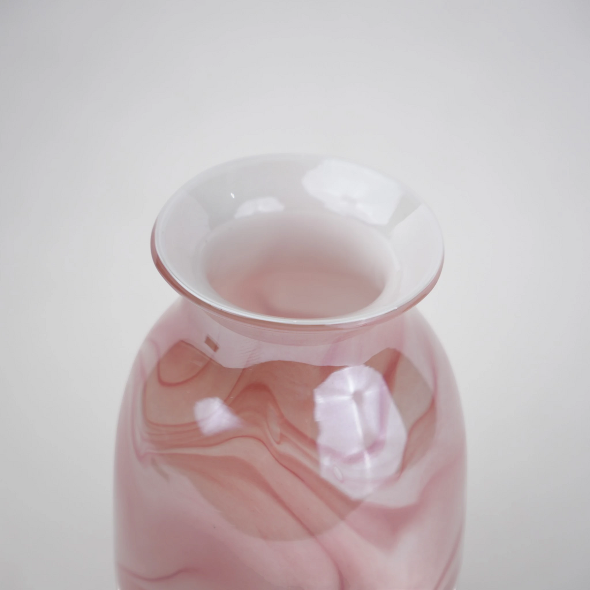 Pink marble glass vase with elongated silhouette and smooth finish.