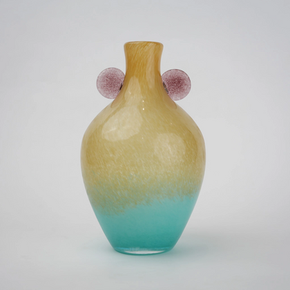 Ombre glass vase with a yellow to teal gradient finish, featuring a rounded body, narrow neck, and decorative side accents, designed as a modern artistic piece for home decor styling.