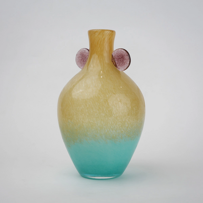 Ombre glass vase with a yellow to teal gradient finish, featuring a rounded body, narrow neck, and decorative side accents, designed as a modern artistic piece for home decor styling.