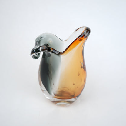 Glass object with gradient color from silver to amber on a white background