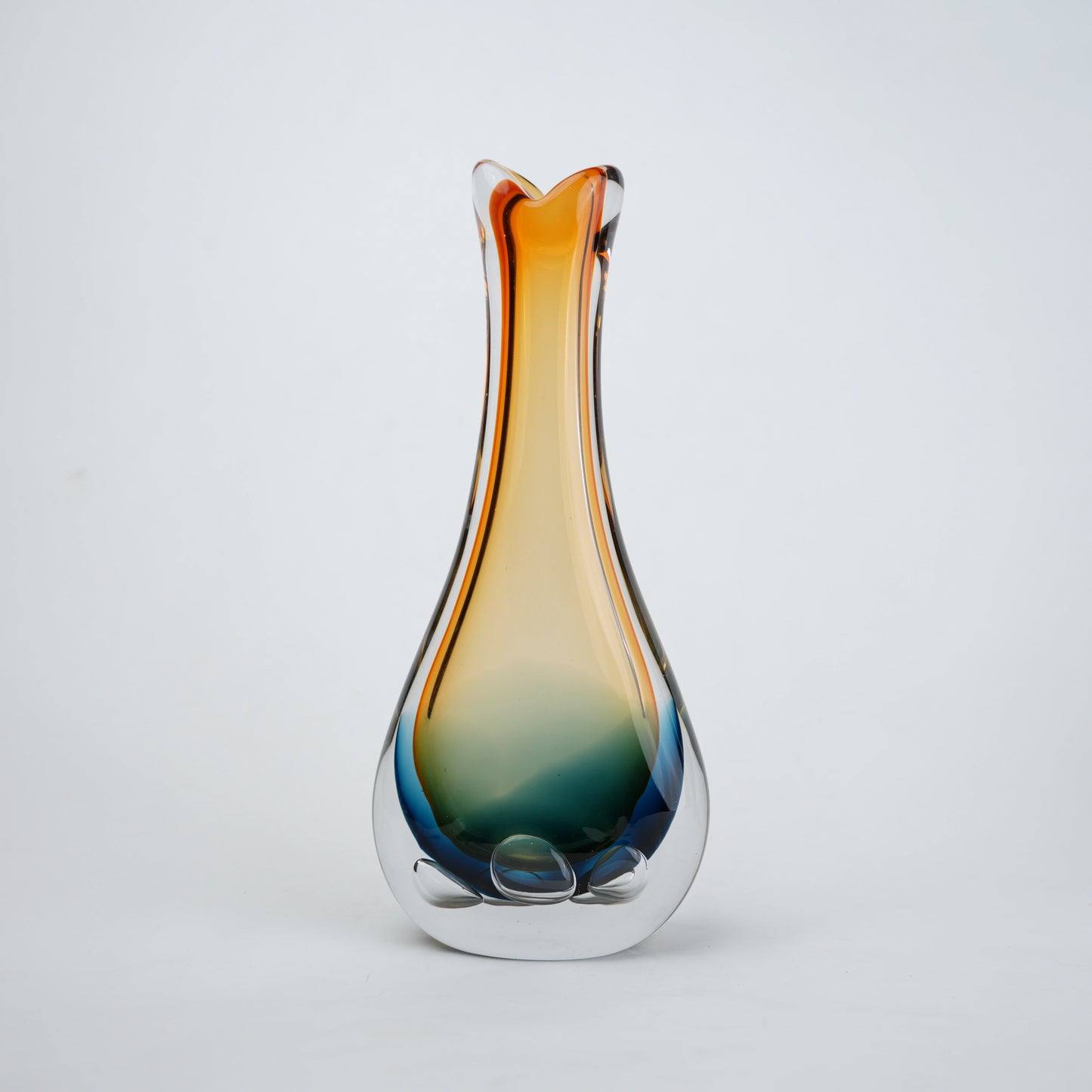 Glass vase with gradient color from orange to blue on a light gray background