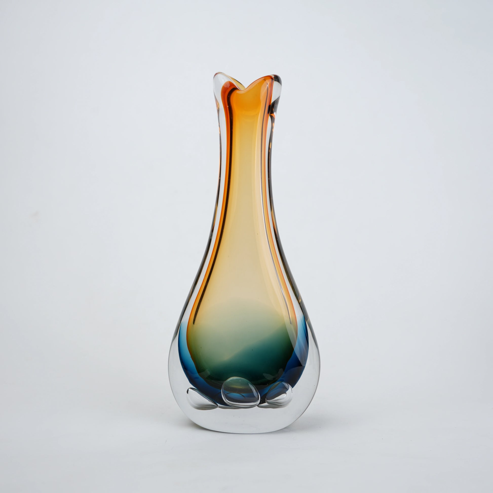 Glass vase with gradient color from orange to blue on a light gray background