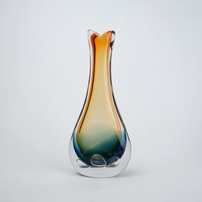 Glass vase with gradient color from orange to blue on a light gray background