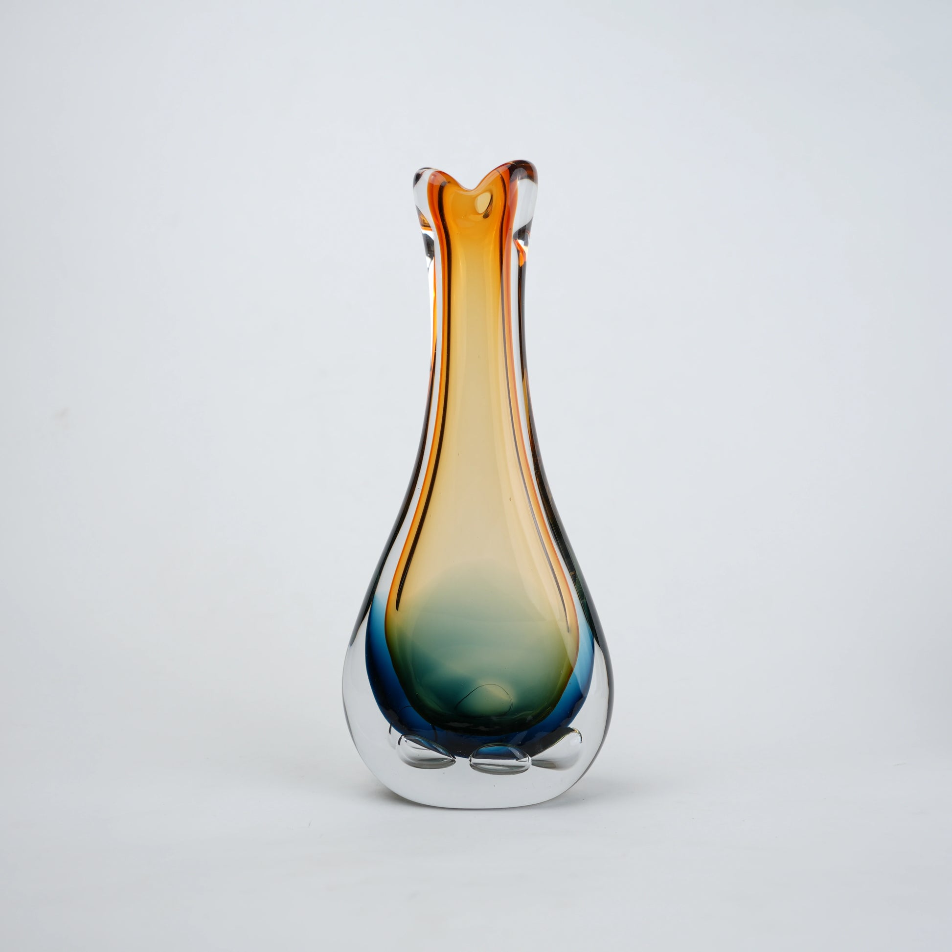 Glass vase with gradient color from blue to orange on a light gray background