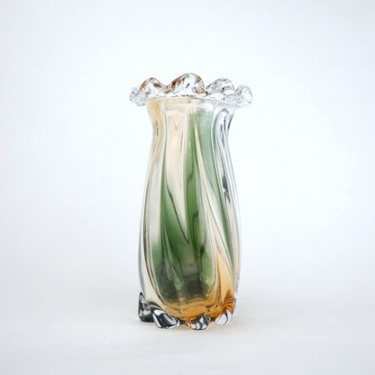 Glass vase with green and amber swirls on a white background