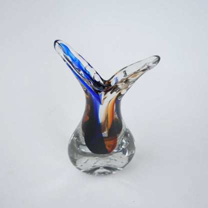 Clear glass decorative vase with asymmetrical flared opening featuring flowing blue and amber color streams inside and textured air bubble detailing at the base.
