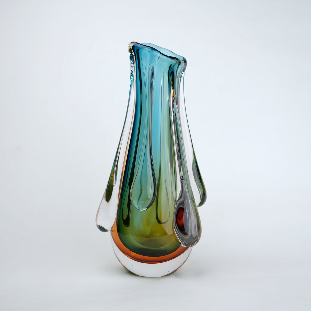 Green and teal glass vase with amber base and flowing drip design in clear glass