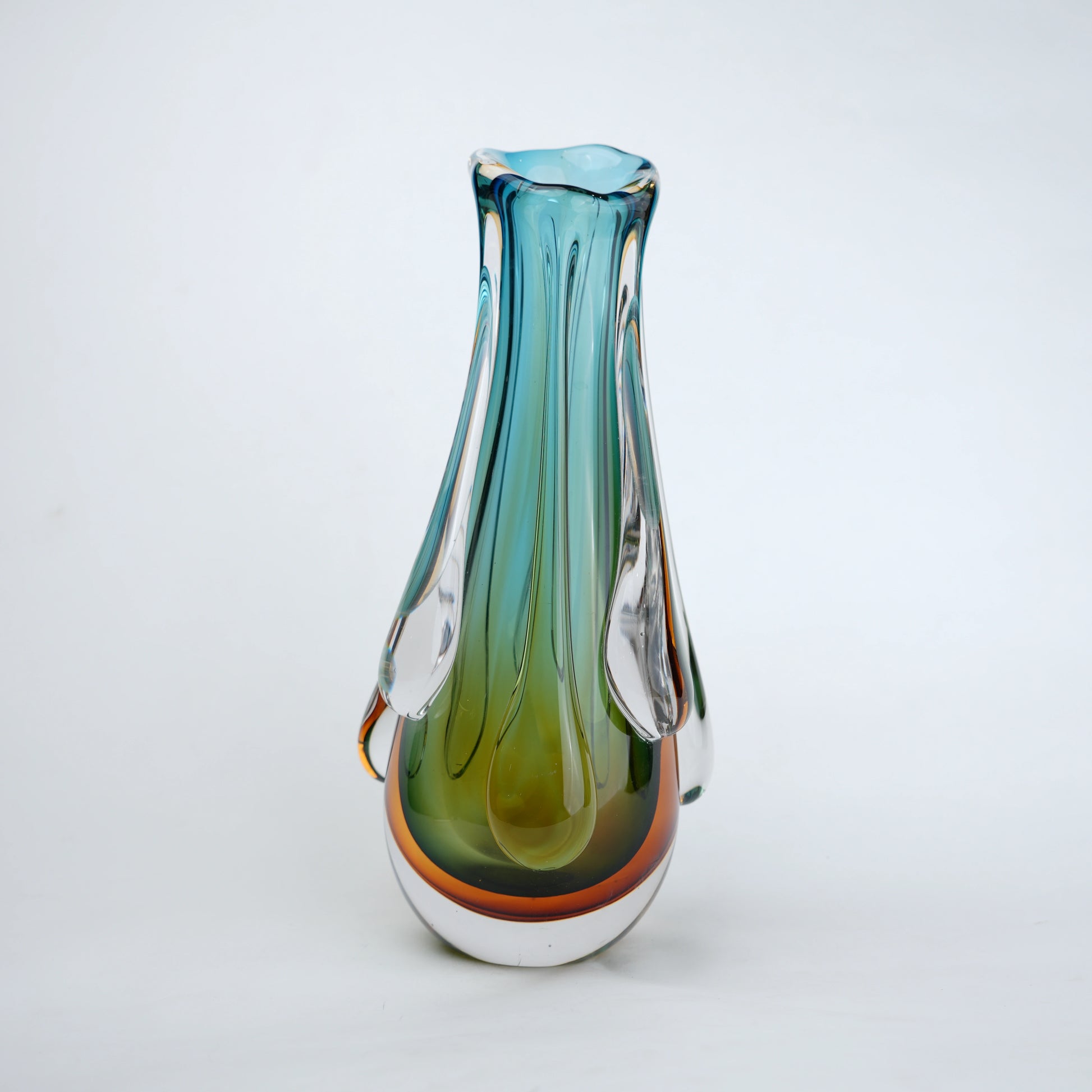 Green and teal glass vase with amber base and flowing drip design in clear glass