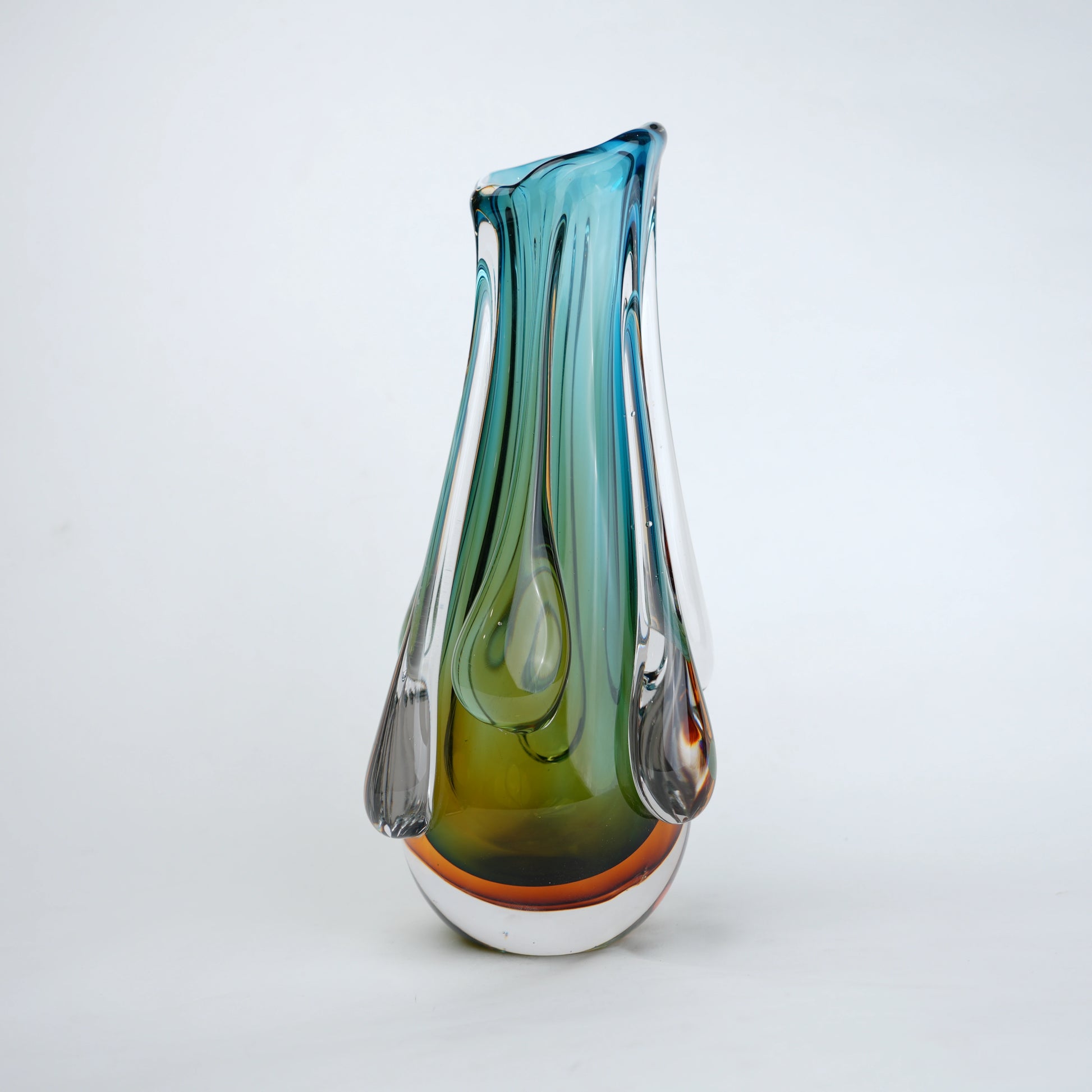 Green and teal glass vase with amber base and flowing drip design in clear glass