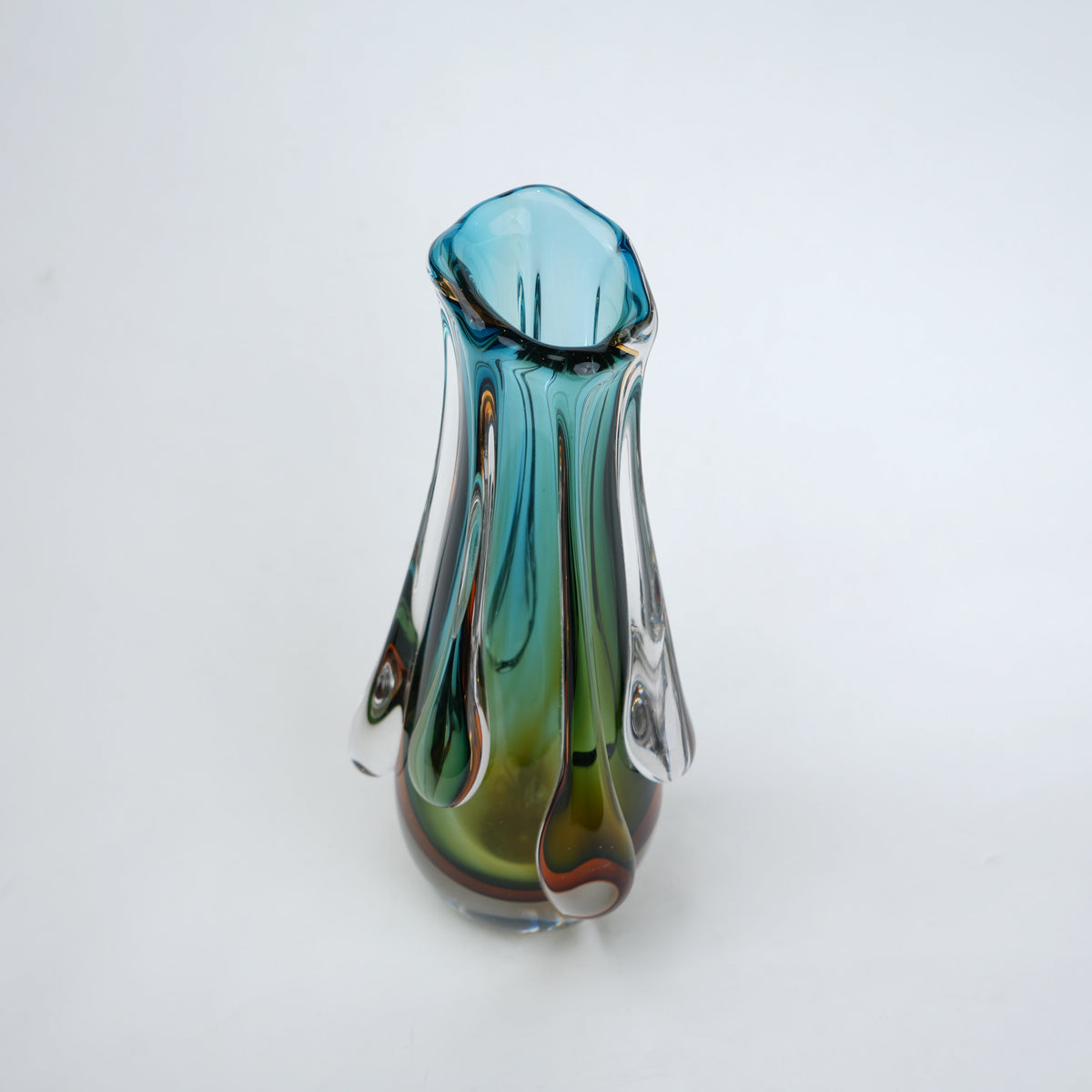 Green and teal glass vase with amber base and flowing drip design in clear glass