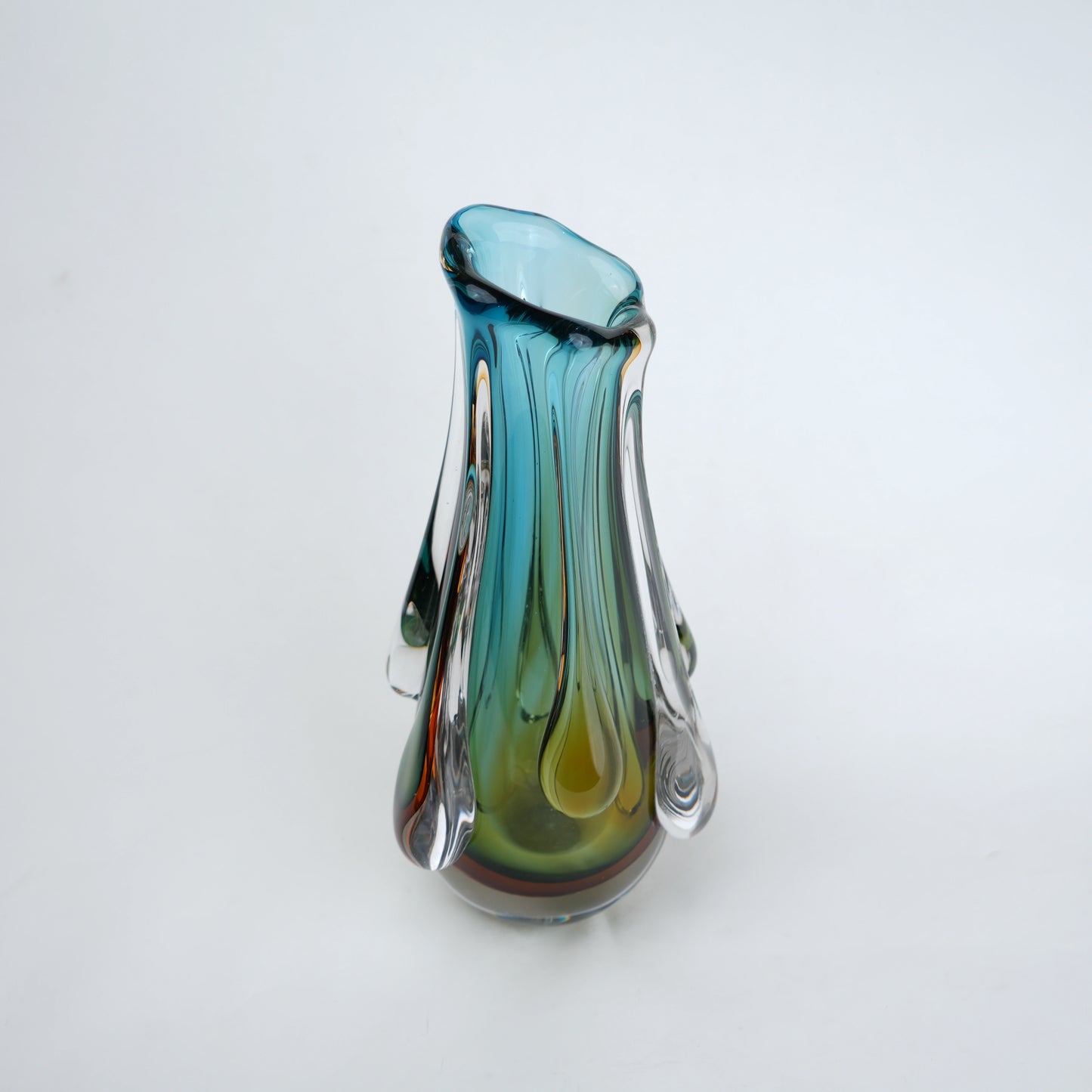 Green and teal glass vase with amber base and flowing drip design in clear glass