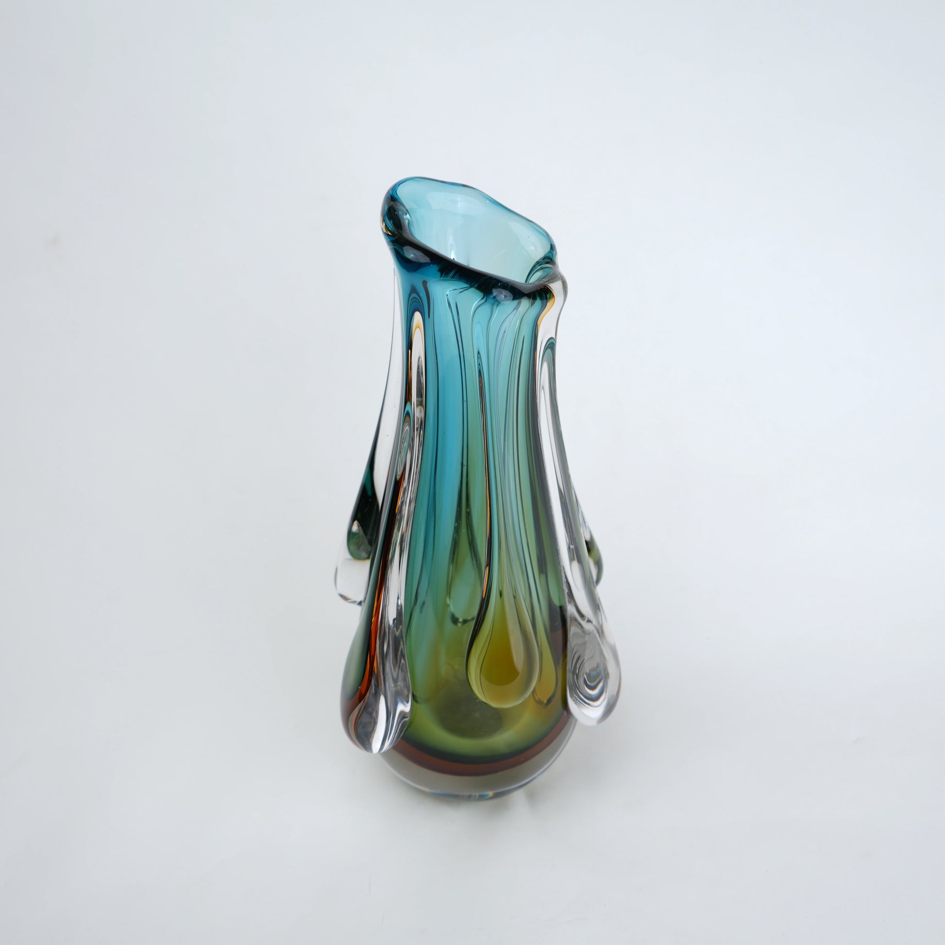 Green and teal glass vase with amber base and flowing drip design in clear glass
