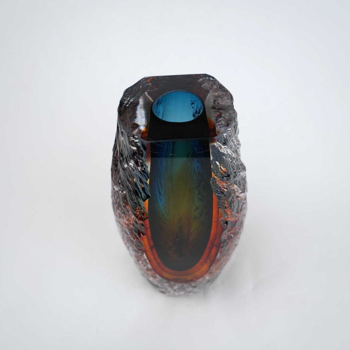 Blue and amber glass vase with textured clear outer layer and cylindrical design