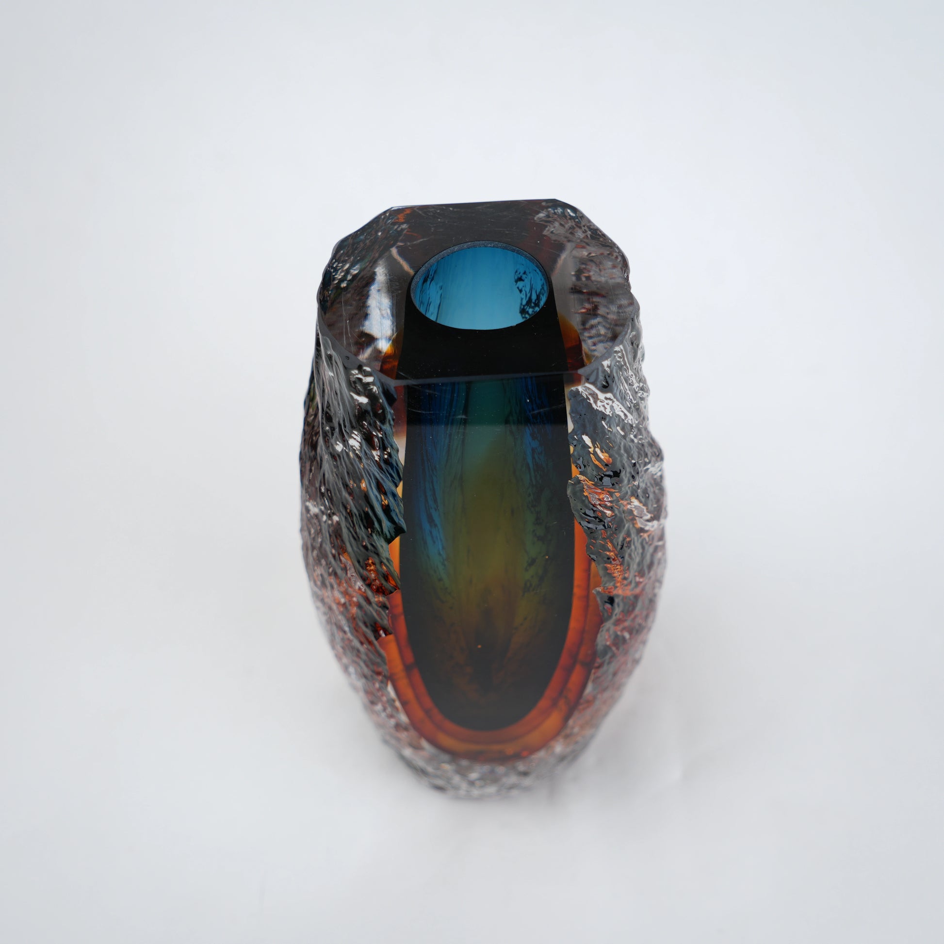 Blue and amber glass vase with textured clear outer layer and cylindrical design