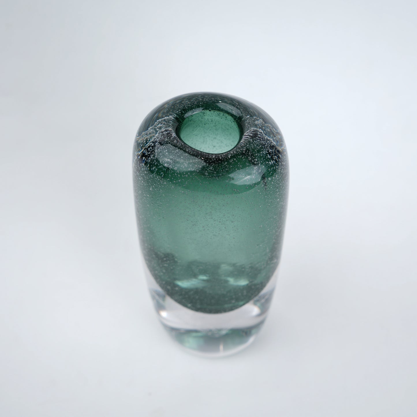 Decorative art glass vase with green gradient center encased inside clear glass body.