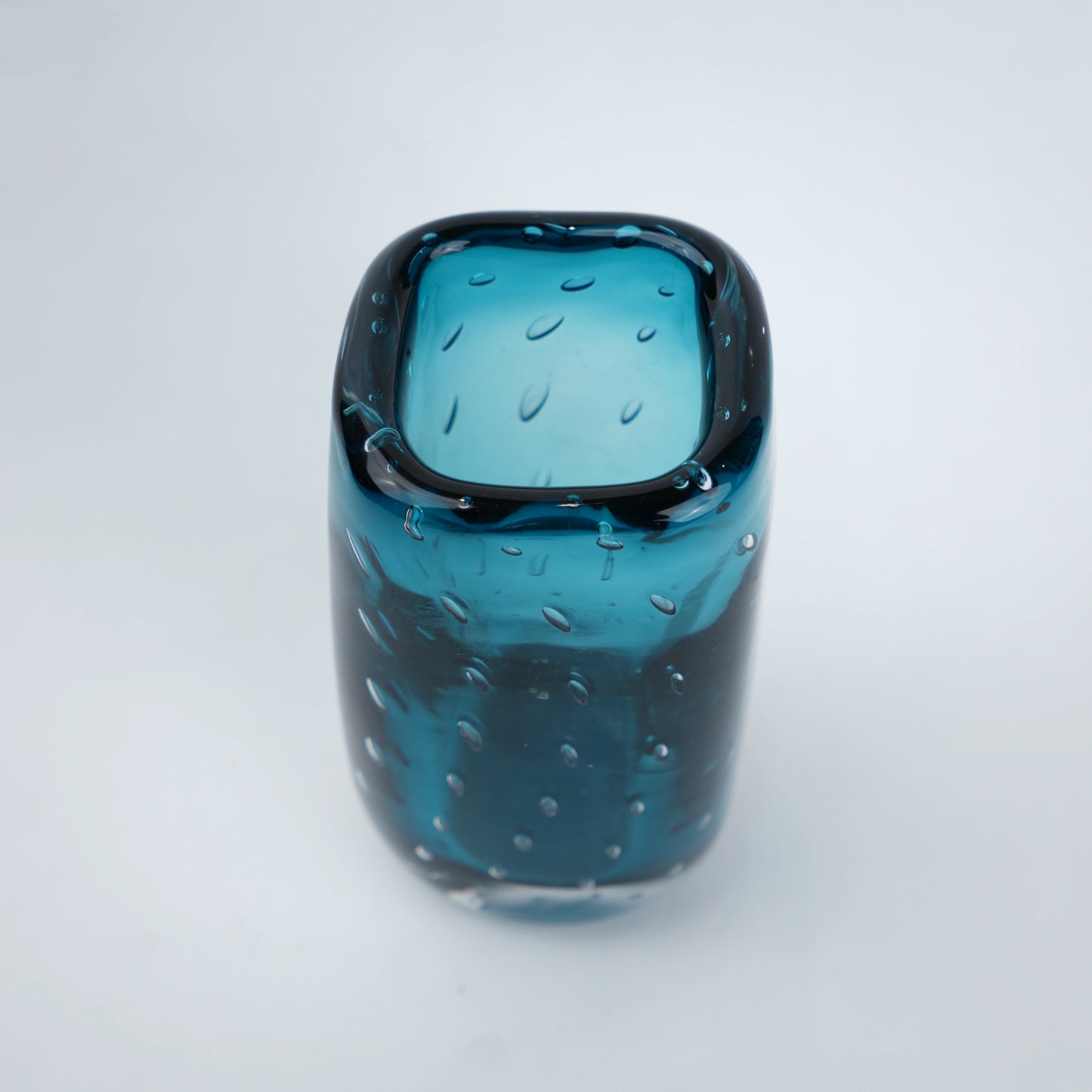 Blue glass vase with textured surface on a white background