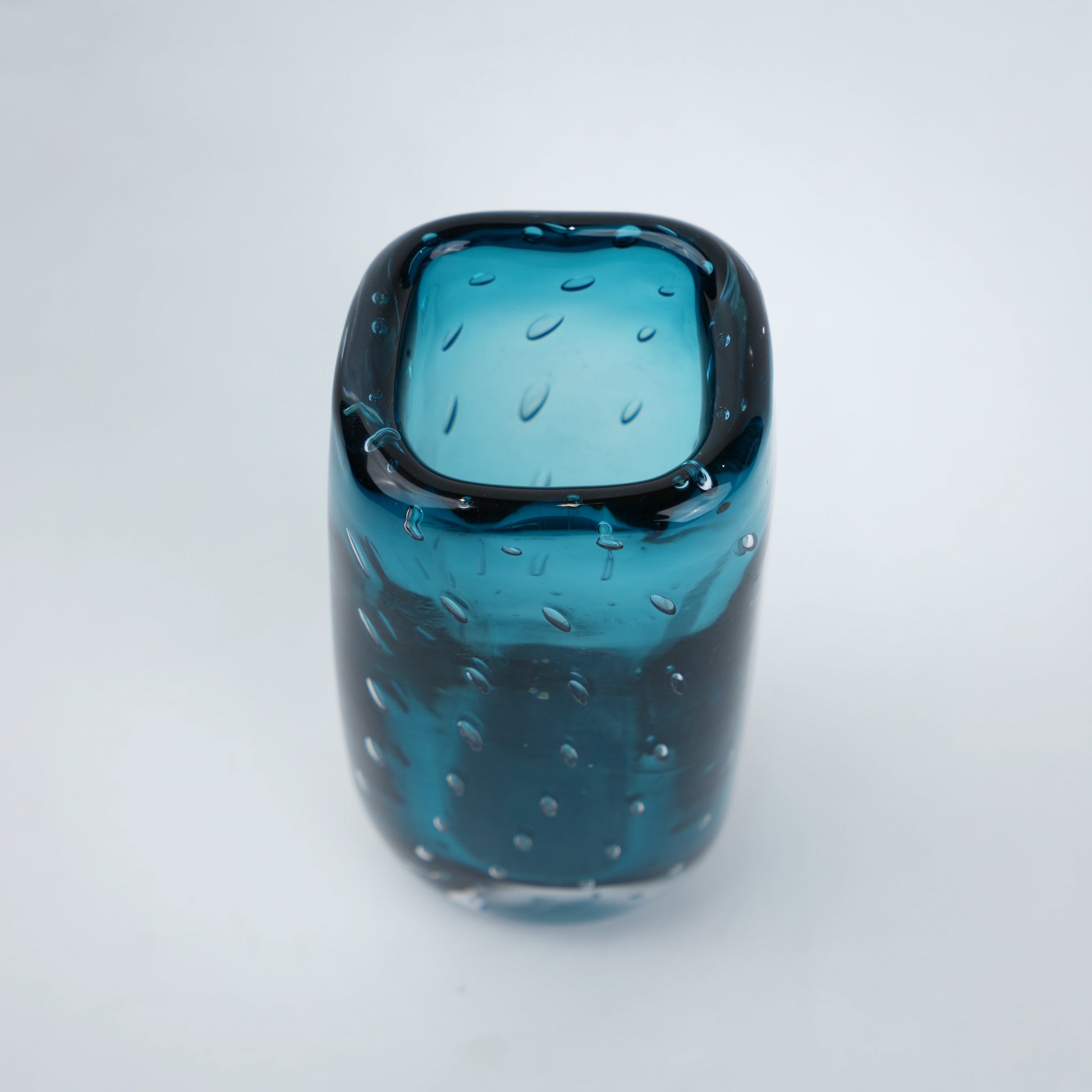 Blue glass vase with textured surface on a white background